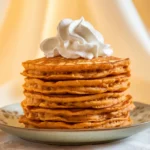 Stack of golden Louisiana sweet potato pancakes drizzled with maple syrup and a pat of butter