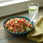 Bowl of Easy Black-Eyed Pea Salad with chopped tomatoes, red and green bell peppers, red onion, celery, and parsley in a light dressing.