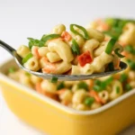 Classic macaroni salad in a bowl with creamy dressing, red bell peppers, celery, carrots, and green onions.