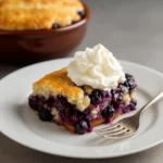 Freshly baked blueberry cobbler in a square dish with golden crust and melted blueberries