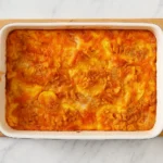 Cheesy squash casserole with golden Ritz cracker topping in a white casserole dish