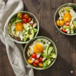 Avocado breakfast bowl with red quinoa, a fried egg, diced avocado and crumbled feta.