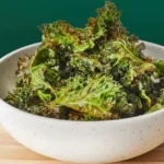 Oven-baked kale chips in a bowl, lightly salted and crisp.