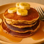 Stack of cottage cheese banana pancakes topped with berries and honey.