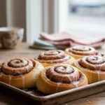 Danish cinnamon snails — cardamom dough rolls with cinnamon filling on parchment.