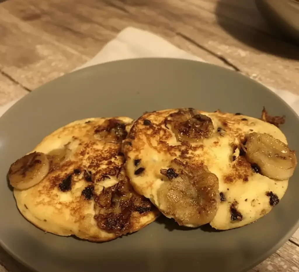 Stack of coconut protein pancakes topped with caramelized banana slices and coconut flakes.