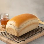 Loaf of honey whole wheat bread sliced on a wooden board.