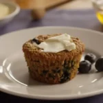 Low-fat blueberry bran muffins on a cooling rack with fresh blueberries scattered around.