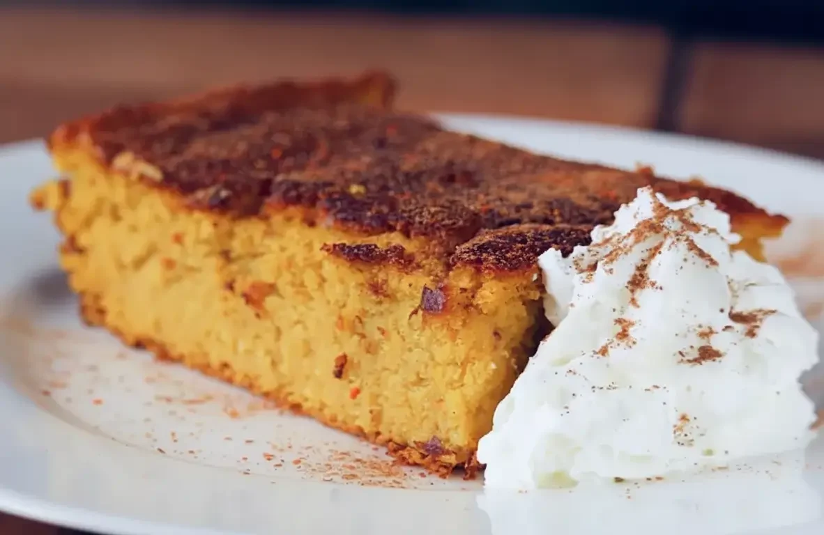 Pumpkin soufflé casserole in a square baking dish dusted with cinnamon.