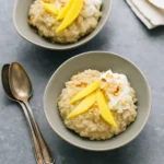 Tropical coconut quinoa pudding topped with mango and toasted coconut in a glass bowl.
